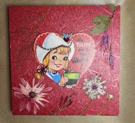 A heart shaped image with pun in the center of pressed flowers set on a red  background